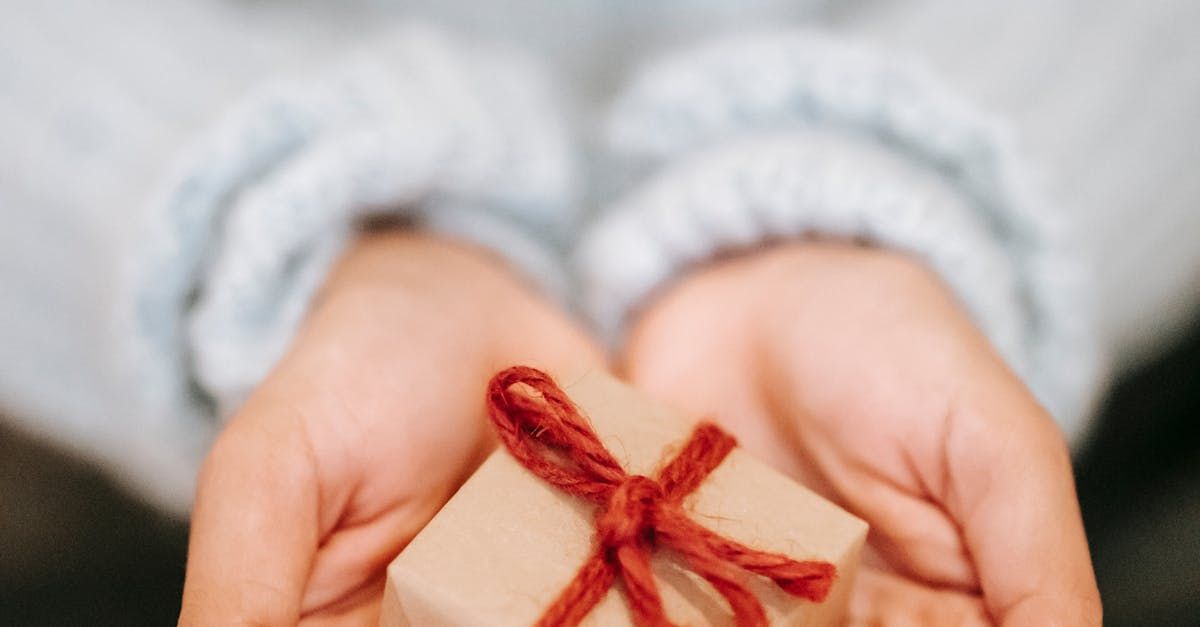 Hands holding a small, wrapped gift tied with red twine.