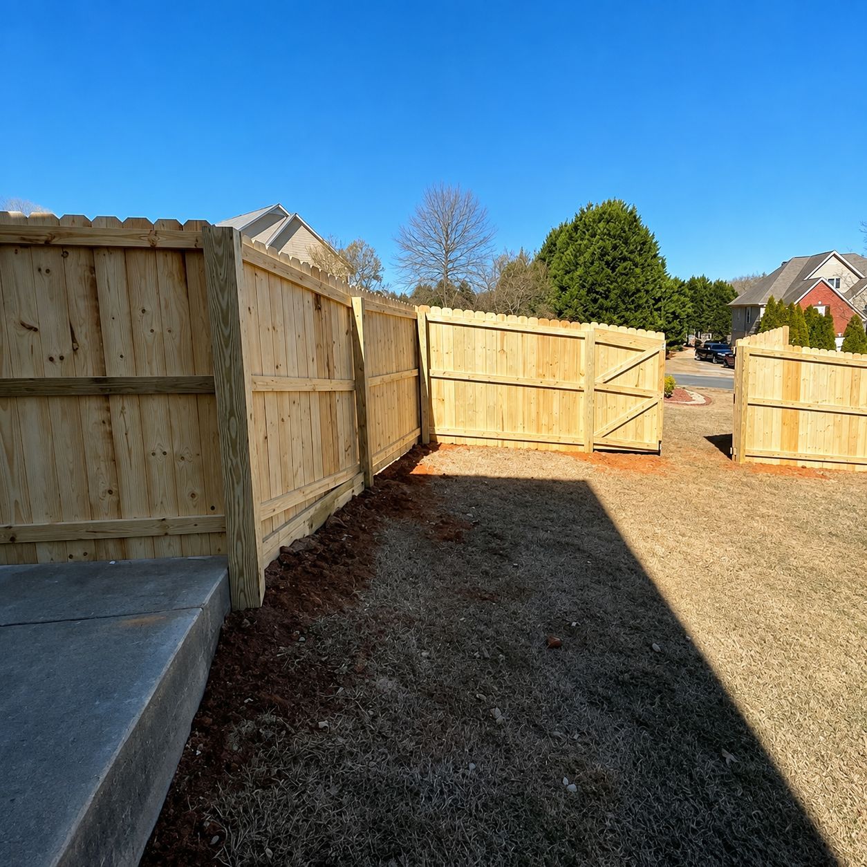 Wooden backyard fence under construction beside a grassy yard on a sunny day