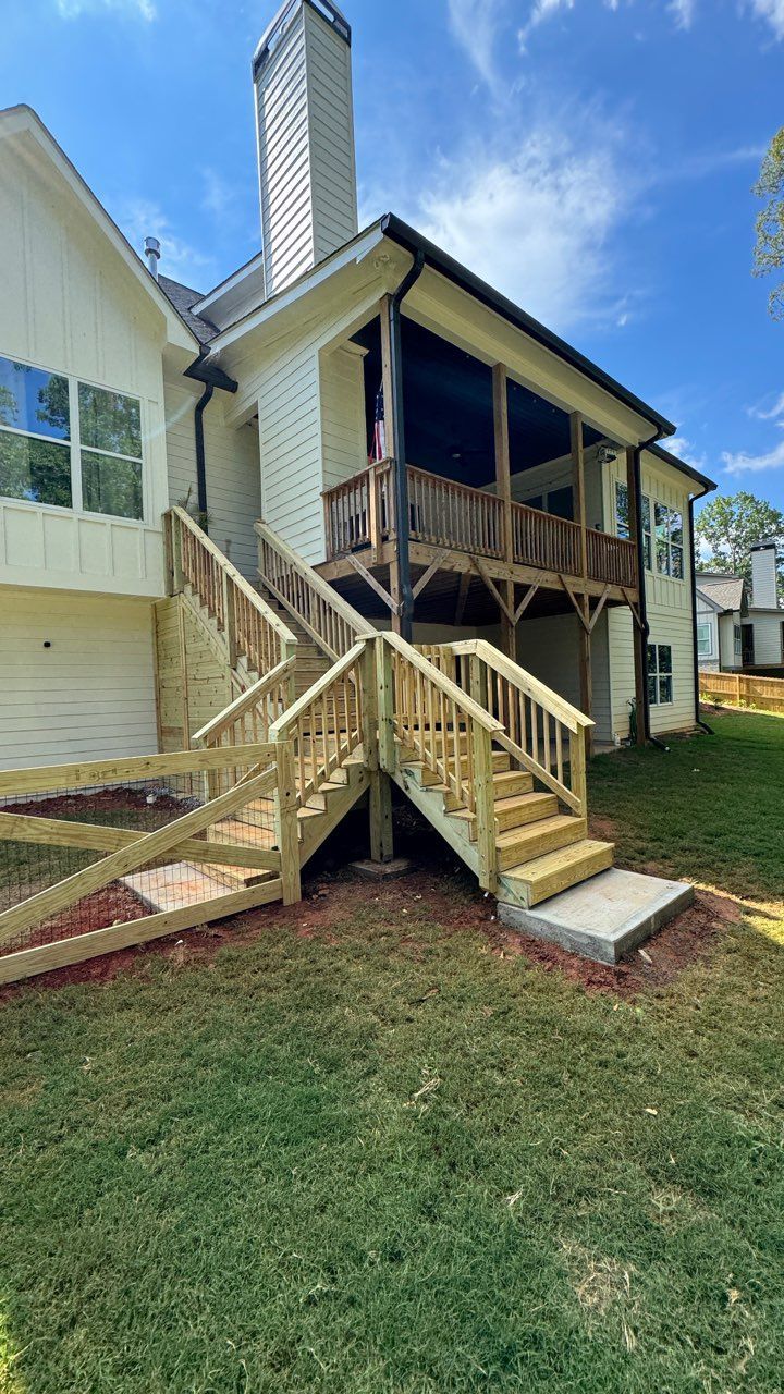 Wooden deck and stairs leading to a two-story house with white siding and a screened porch.