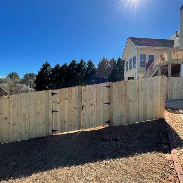 Wooden fence with gate, sunny blue sky, and a house in the background.
