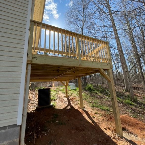 Wooden deck attached to a house, supported by posts. Sunlight, outdoor setting.