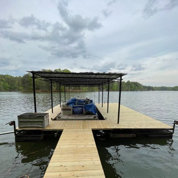 Wooden dock on a lake with a covered boat slip, overcast sky.