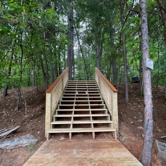 Wooden staircase leading up a hill through a forest.