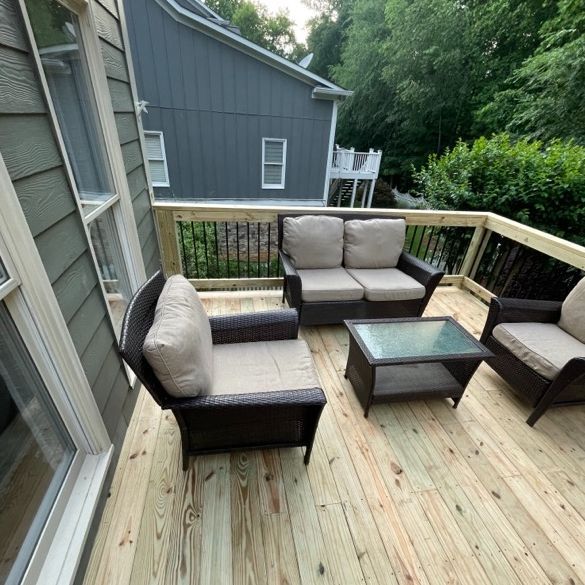 Outdoor deck with wicker furniture and tan cushions.