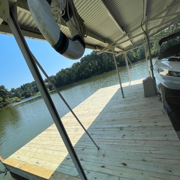 A wooden dock with a covered roof, overlooking a lake. A life preserver hangs above.
