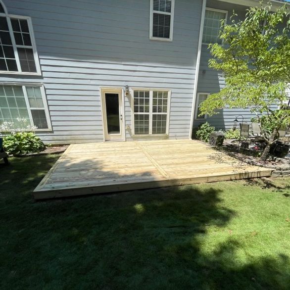Wooden deck attached to a light blue house, accessible through a sliding glass door.