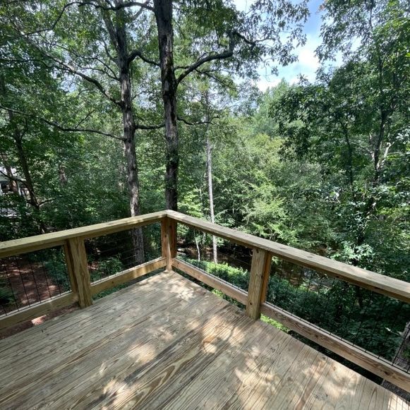 Wooden deck overlooking a wooded area with trees and foliage.