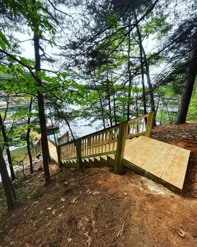 Wooden staircase leading down a hill to a lake, surrounded by trees.