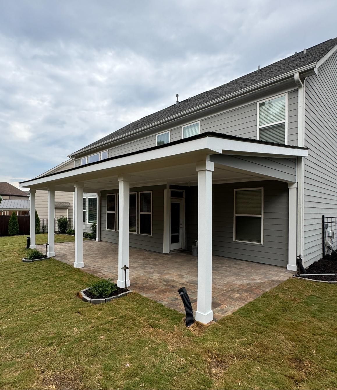 Backyard patio with light gray siding and white columns.
