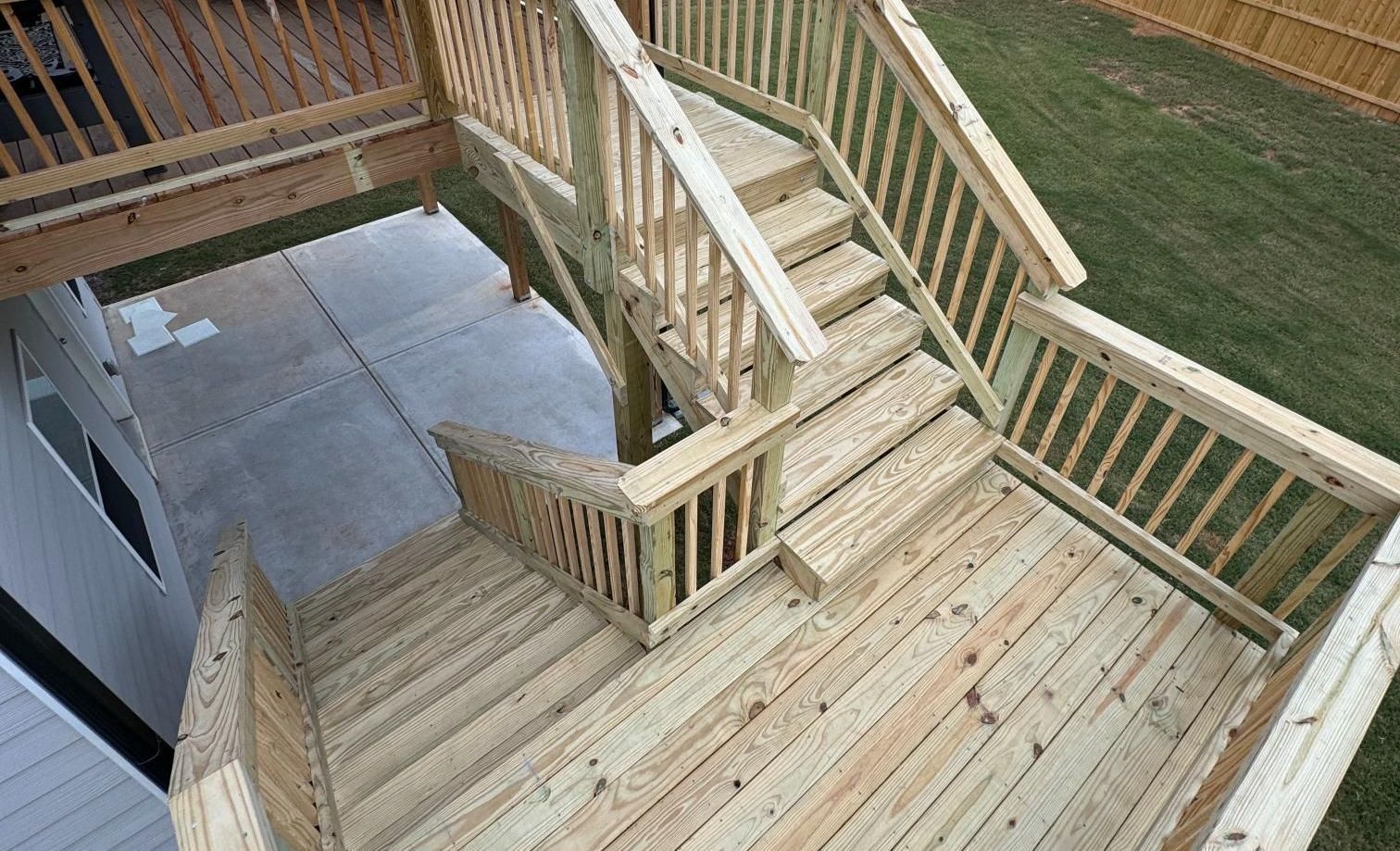 Wooden deck with stairs leading to a lower level. The deck and stairs are light brown.