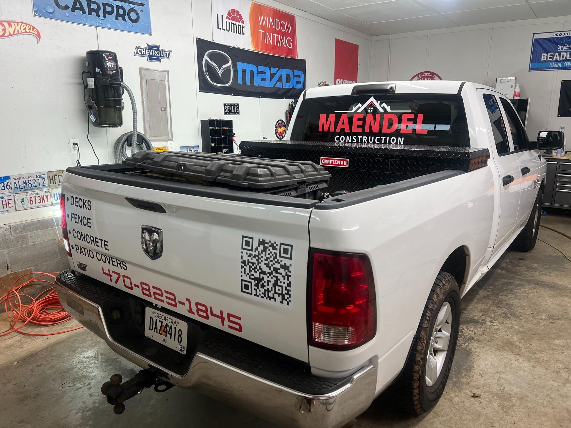 White Dodge Ram truck in a garage; red lettering for business signage, QR code on rear.
