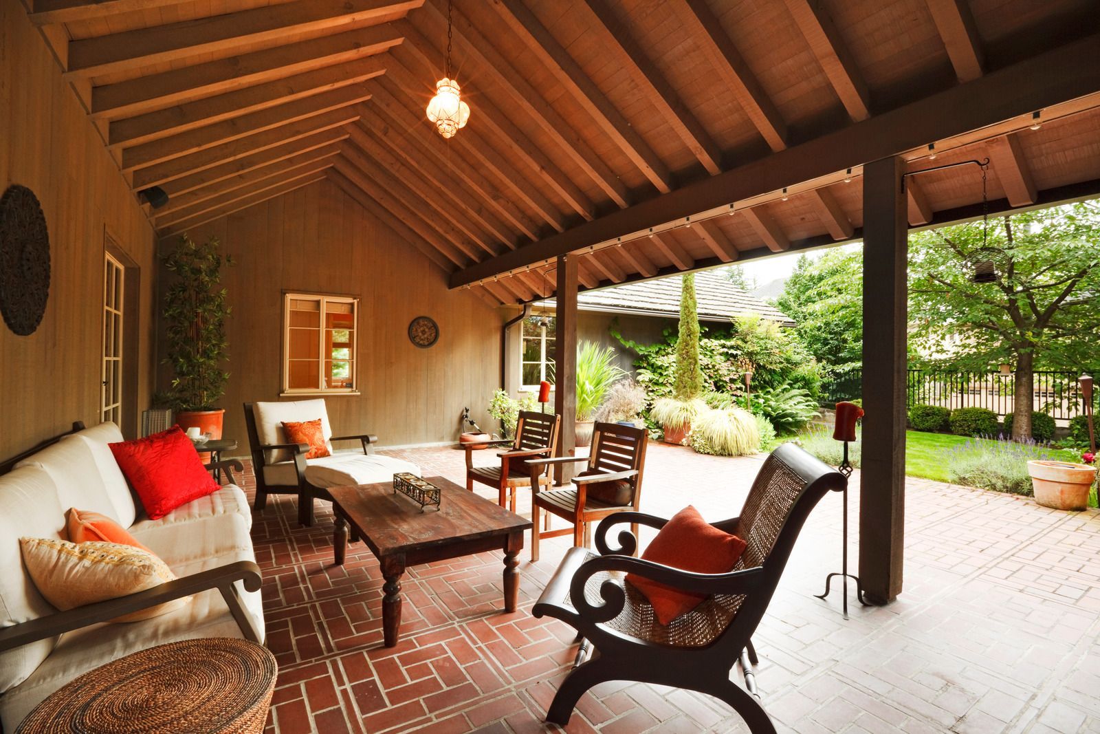 Covered outdoor patio with seating and a view of a garden.