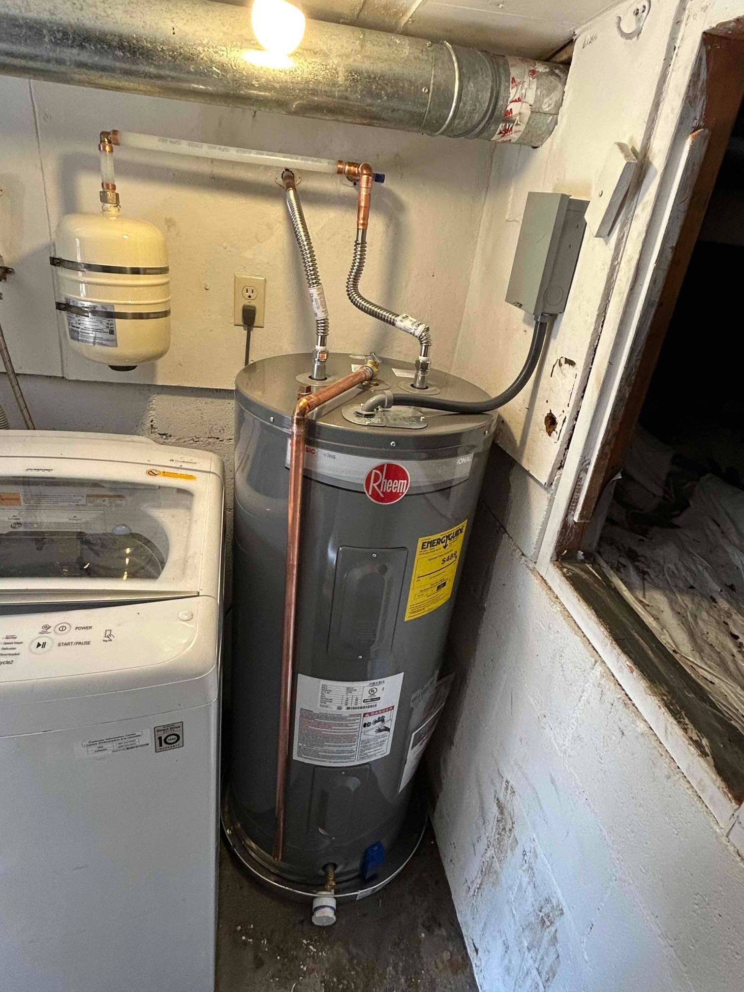 Water heater in a narrow utility closet beside pipes, valves, and a small tank near a doorway.