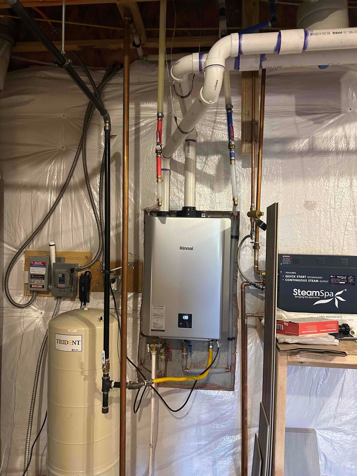 Wall-mounted water heater and HVAC piping in a basement utility room.