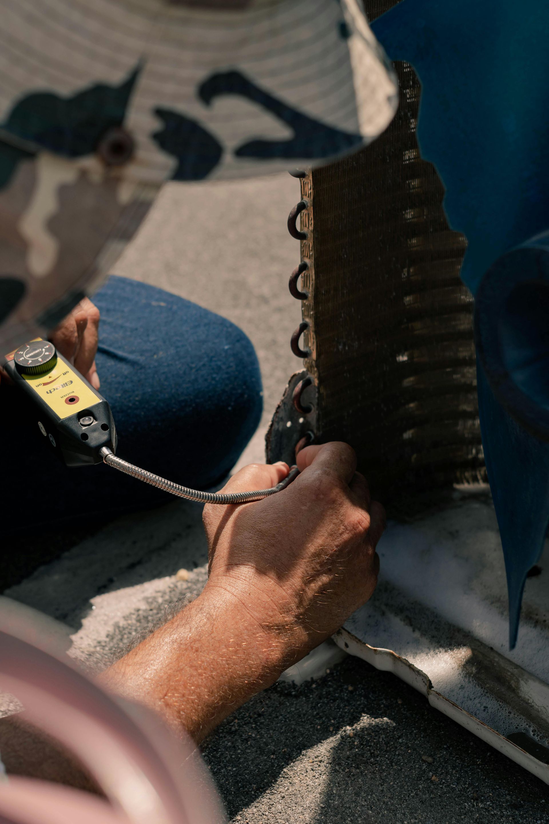 Hands working on a metal panel with a measuring tape and wires in a workshop.