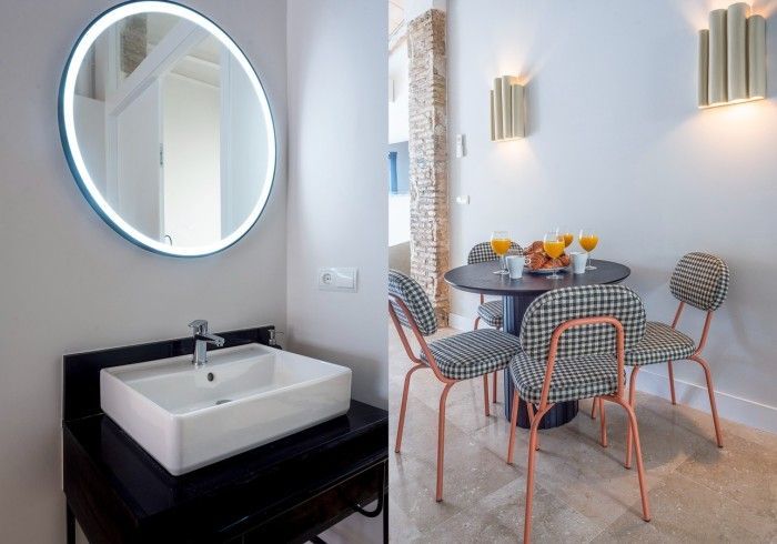 Rincón de comedor moderno con mesa redonda, sillas estampadas y tocador negro con espejo redondo y lavabo.