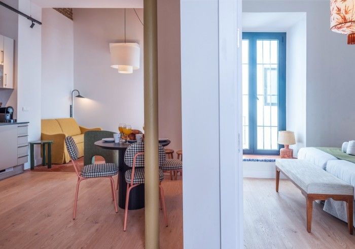 Interior de un apartamento moderno con zona de comedor a la izquierda y dormitorio luminoso a la derecha.