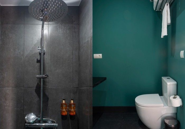 Baño moderno con ducha a ras de suelo, pared color turquesa y inodoro blanco a la derecha.
