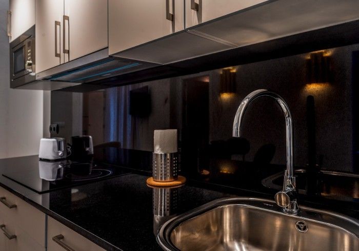 Encimera de cocina moderna con fregadero, grifo, cafetera y armarios con iluminación bajo los armarios.