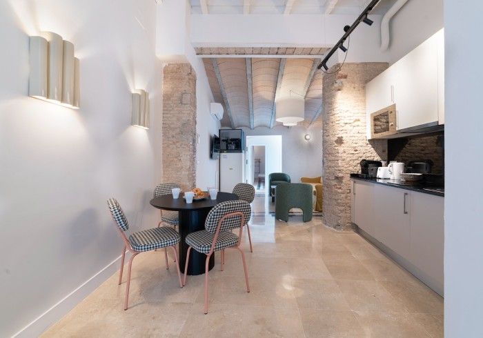 Cocina y comedor modernos con paredes de ladrillo visto, armarios negros y una pequeña mesa redonda con sillas.