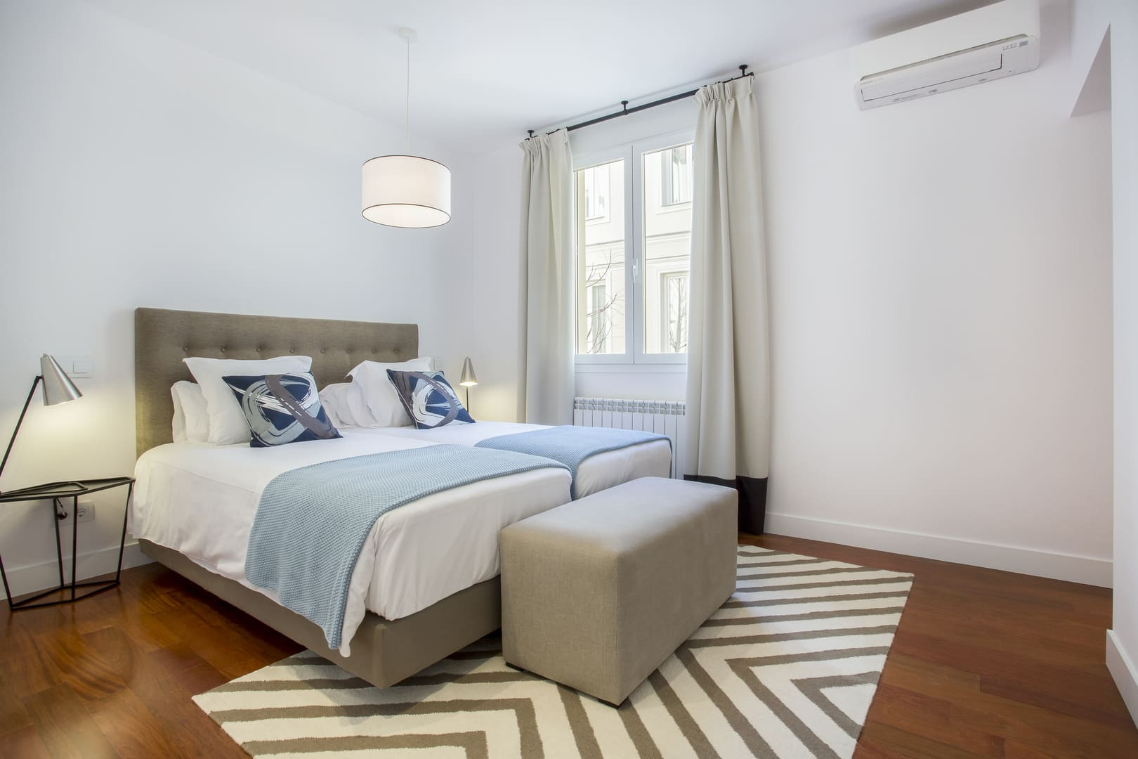 Sala de estar moderna y luminosa con sofá color mostaza, sillón azul, mesa de centro y encimera de cocina.