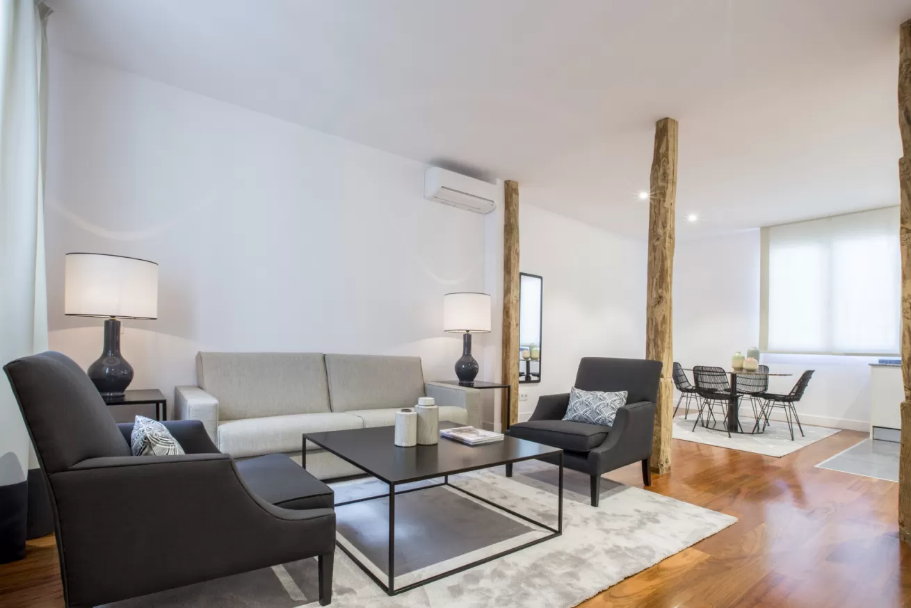 Sala de estar moderna con sofá gris, sillas negras, mesa de centro, lámpara de pie y suelo de madera.