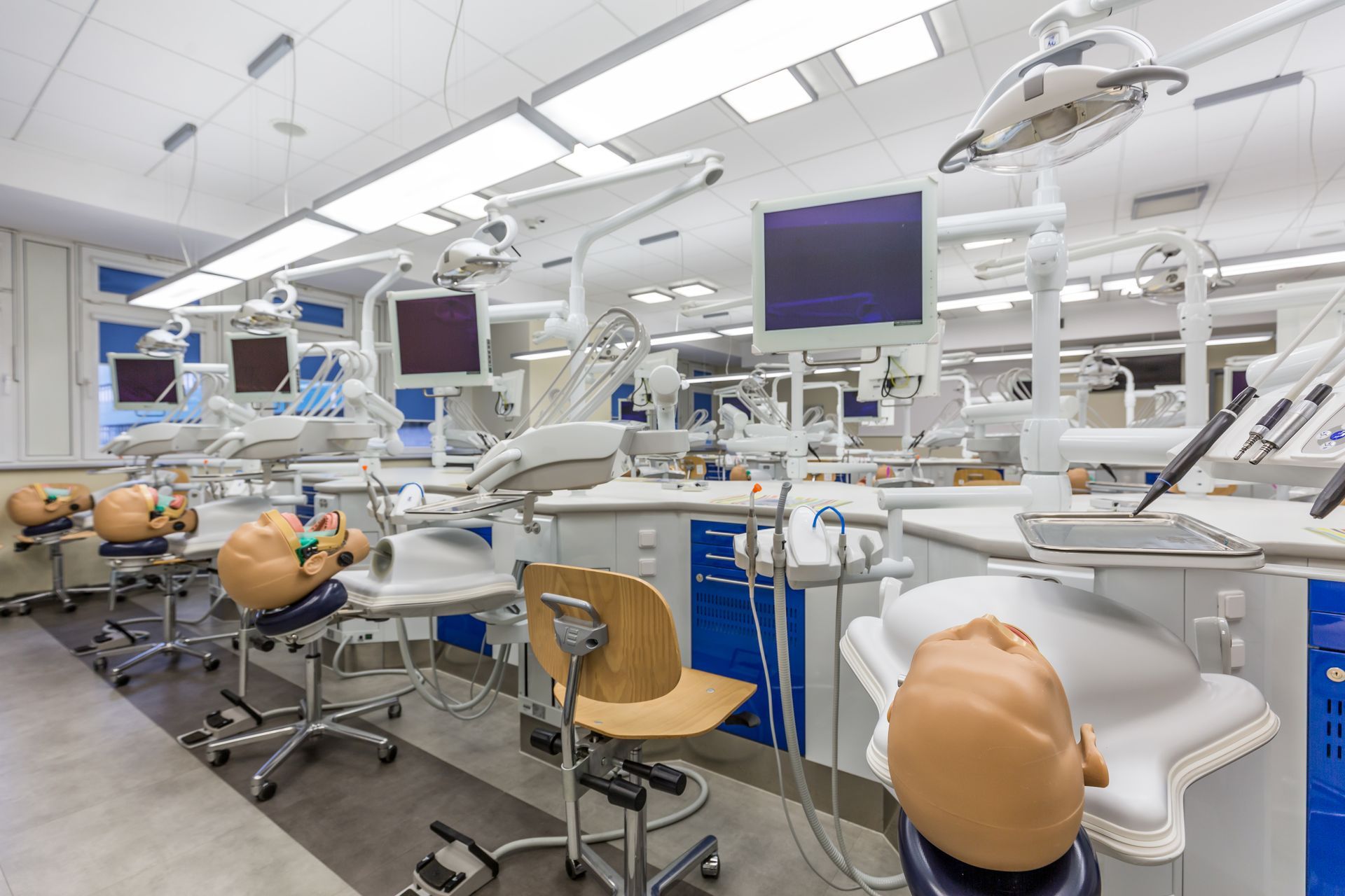 Dental school lab with mannequins, dental chairs, and equipment. Bright, clean space.