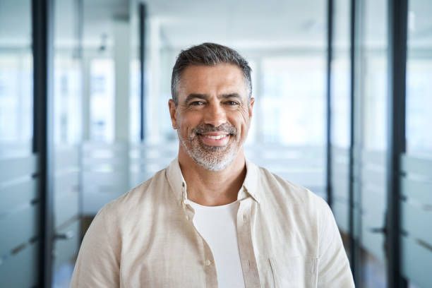 Smiling man standing in a bright office hallway with glass walls