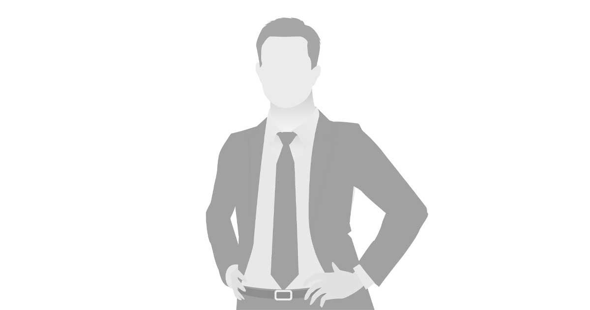 A man in a suit and tie is standing with his hands on his hips.