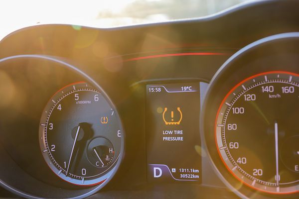 Car dashboard with a low tire pressure warning light illuminated.