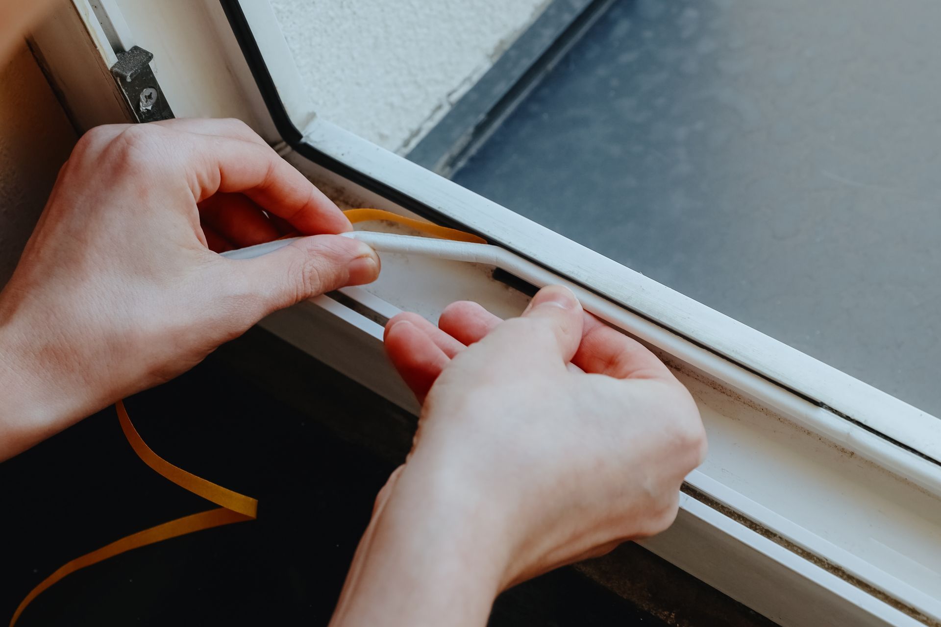 Hands fastening a wooden window latch next to a glass pane