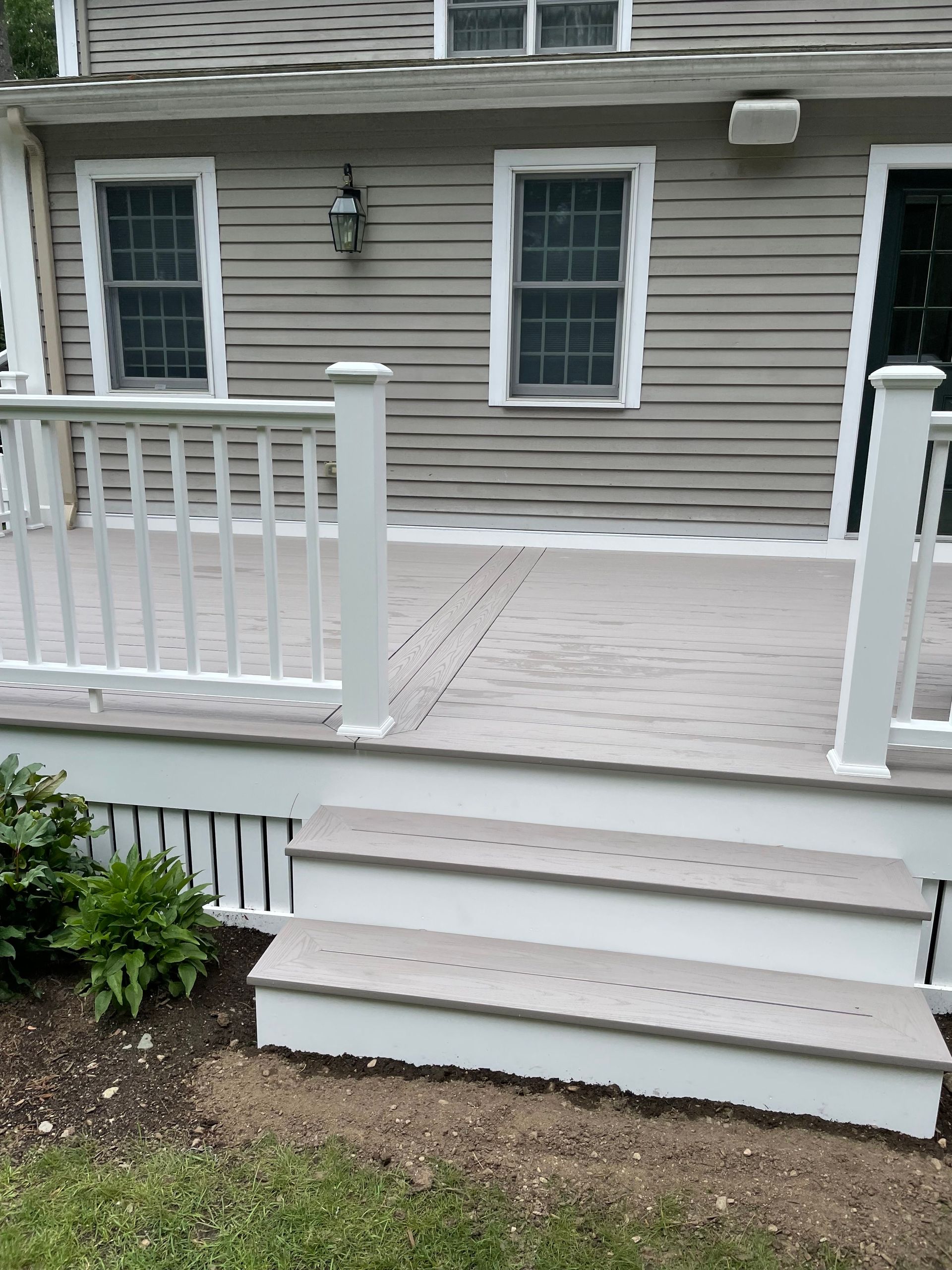 White-railed wooden porch with steps and beige house siding