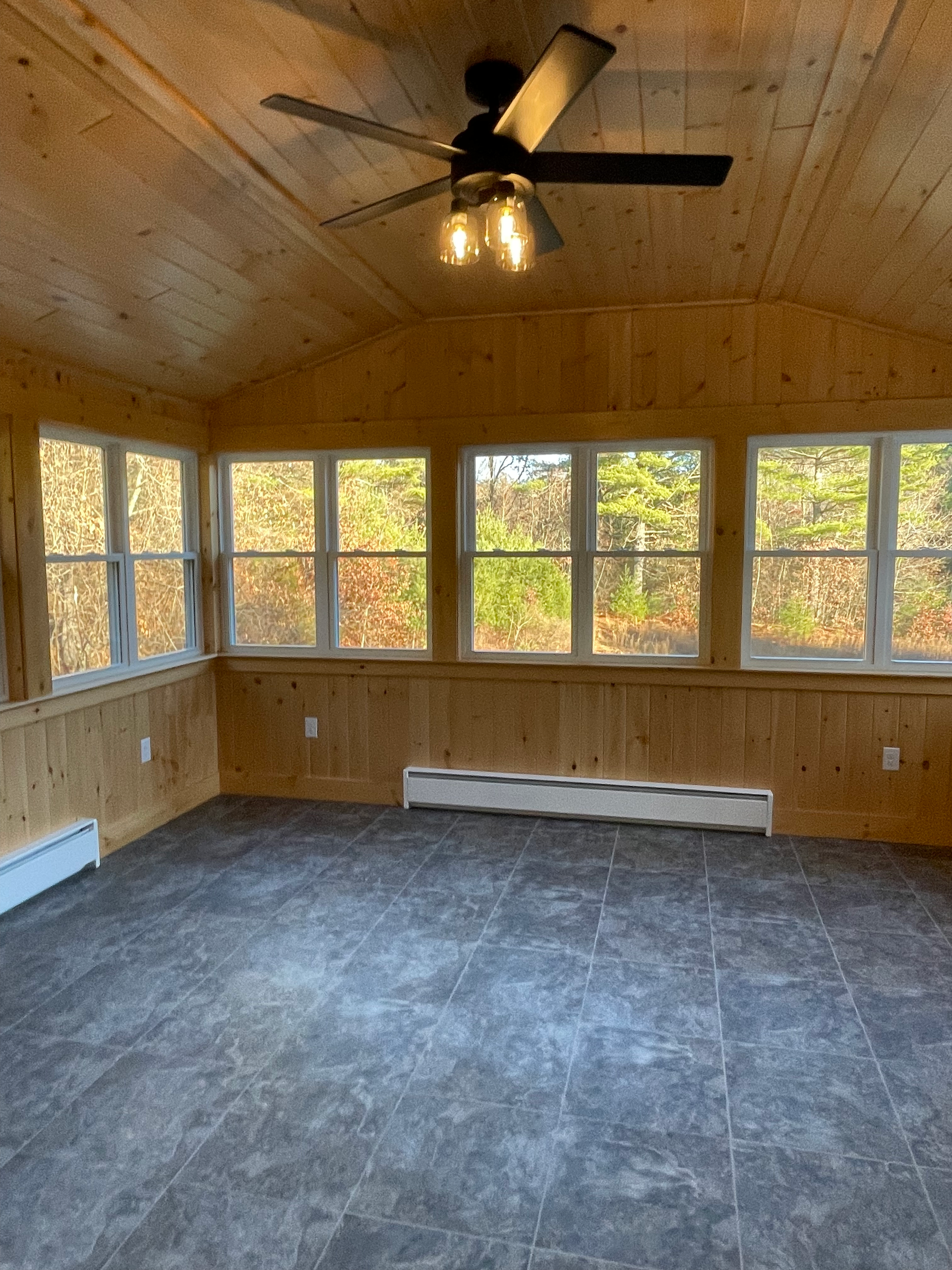 An empty room with a ceiling fan and lots of windows