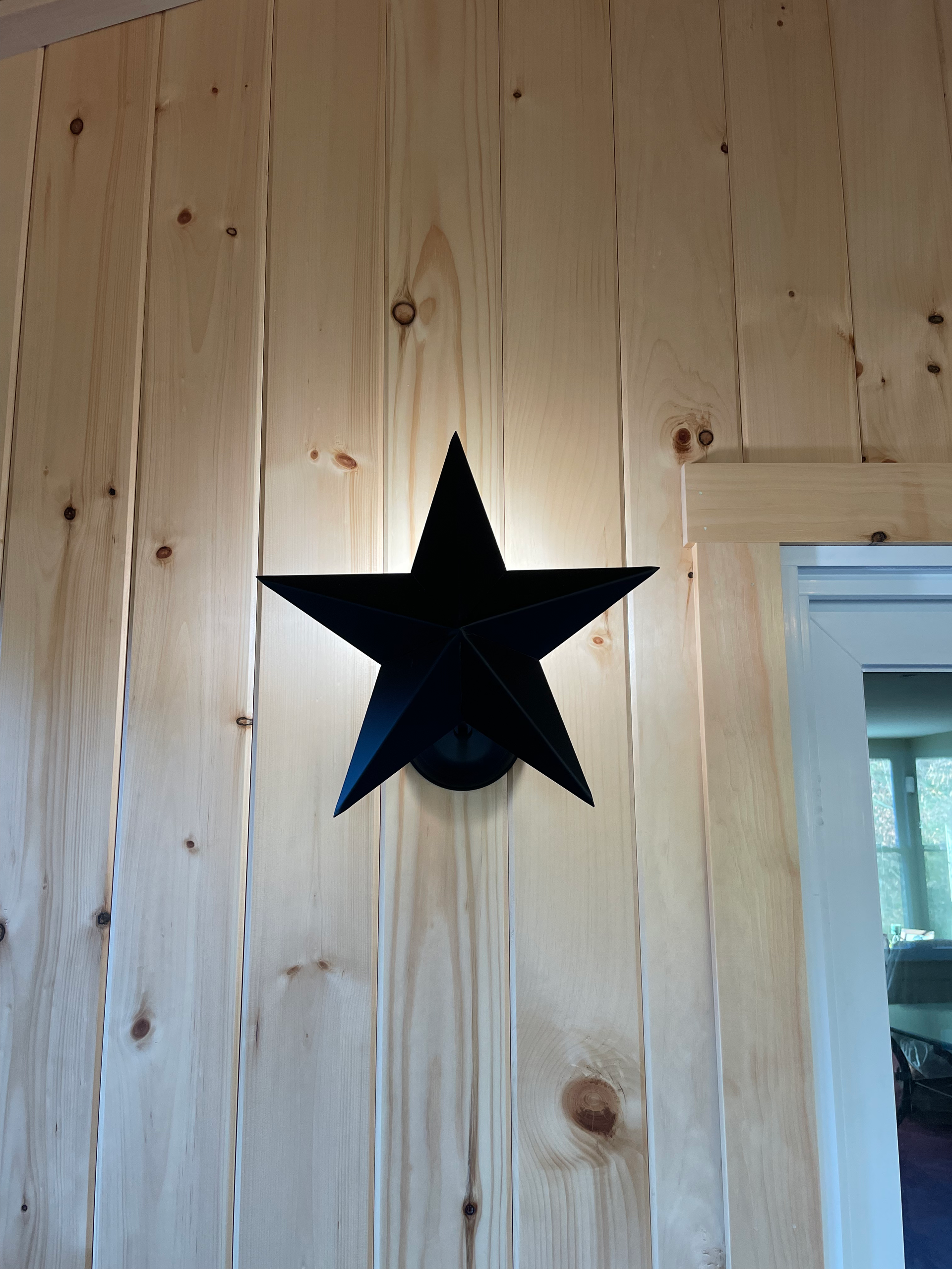 A black star is hanging on a wooden wall