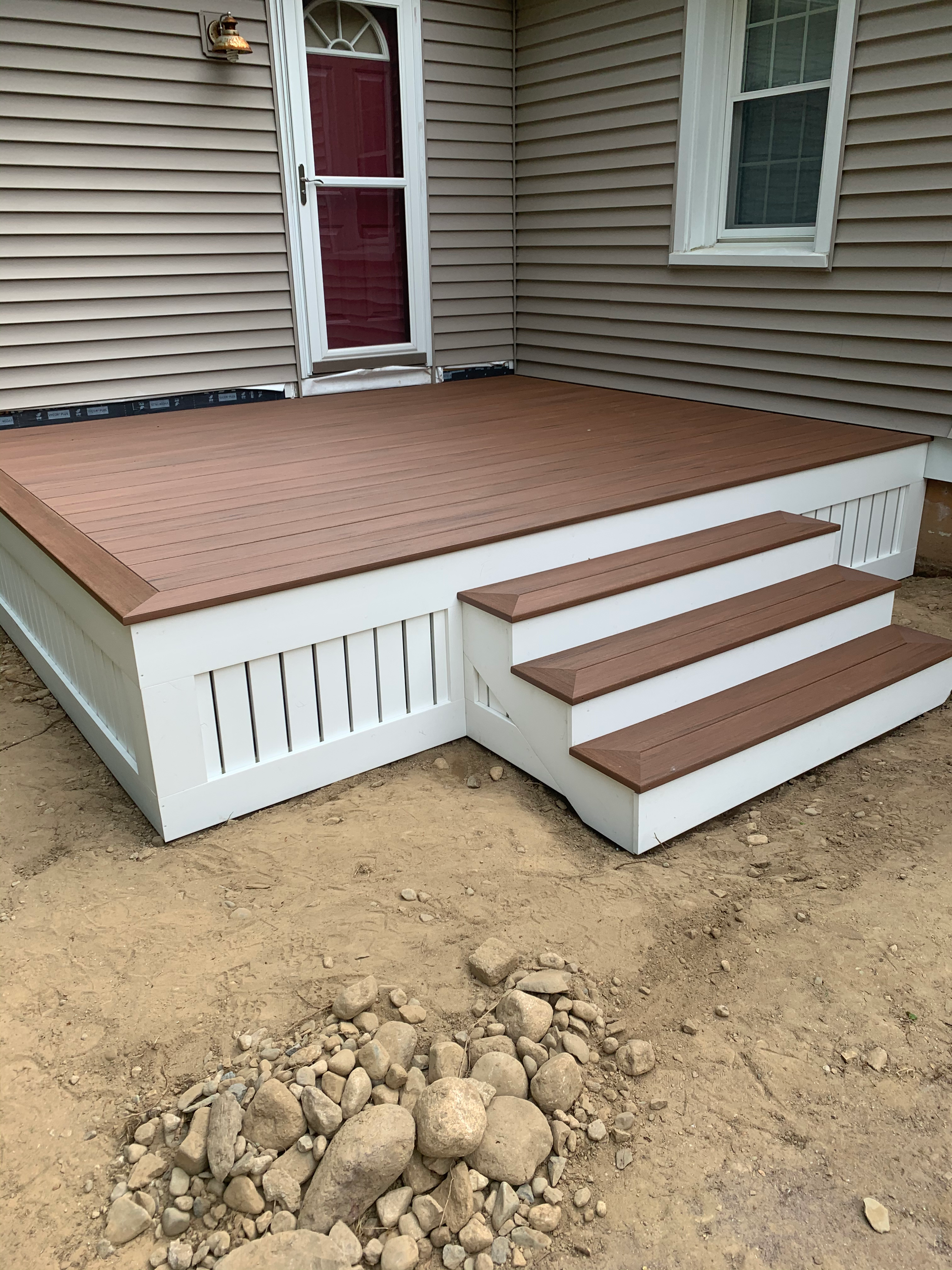A wooden deck with stairs is in front of a house.