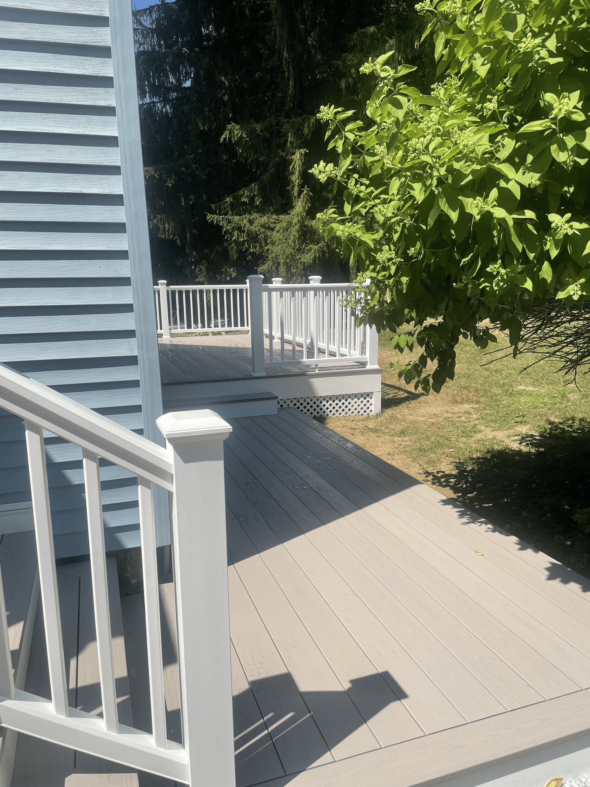 A white staircase leading up to a deck with a white railing.