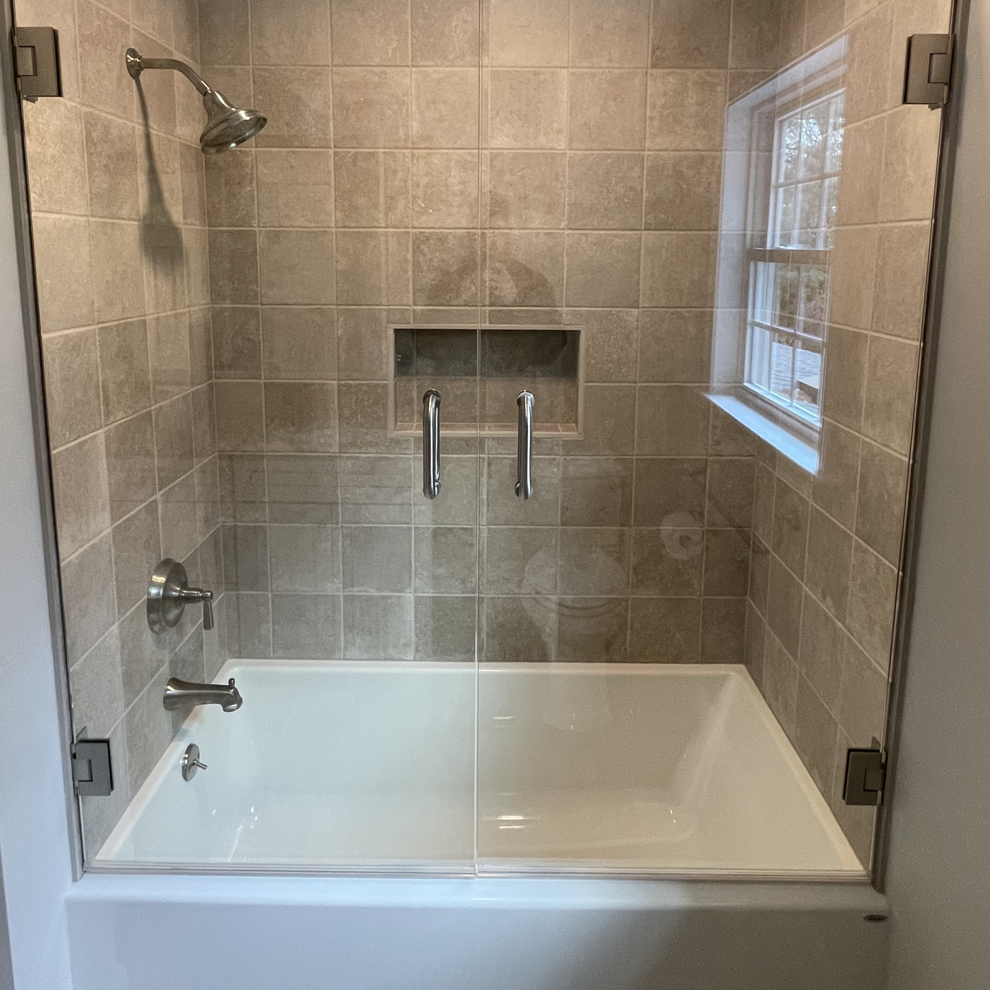 A bathroom with a bathtub and a shower with a glass door.
