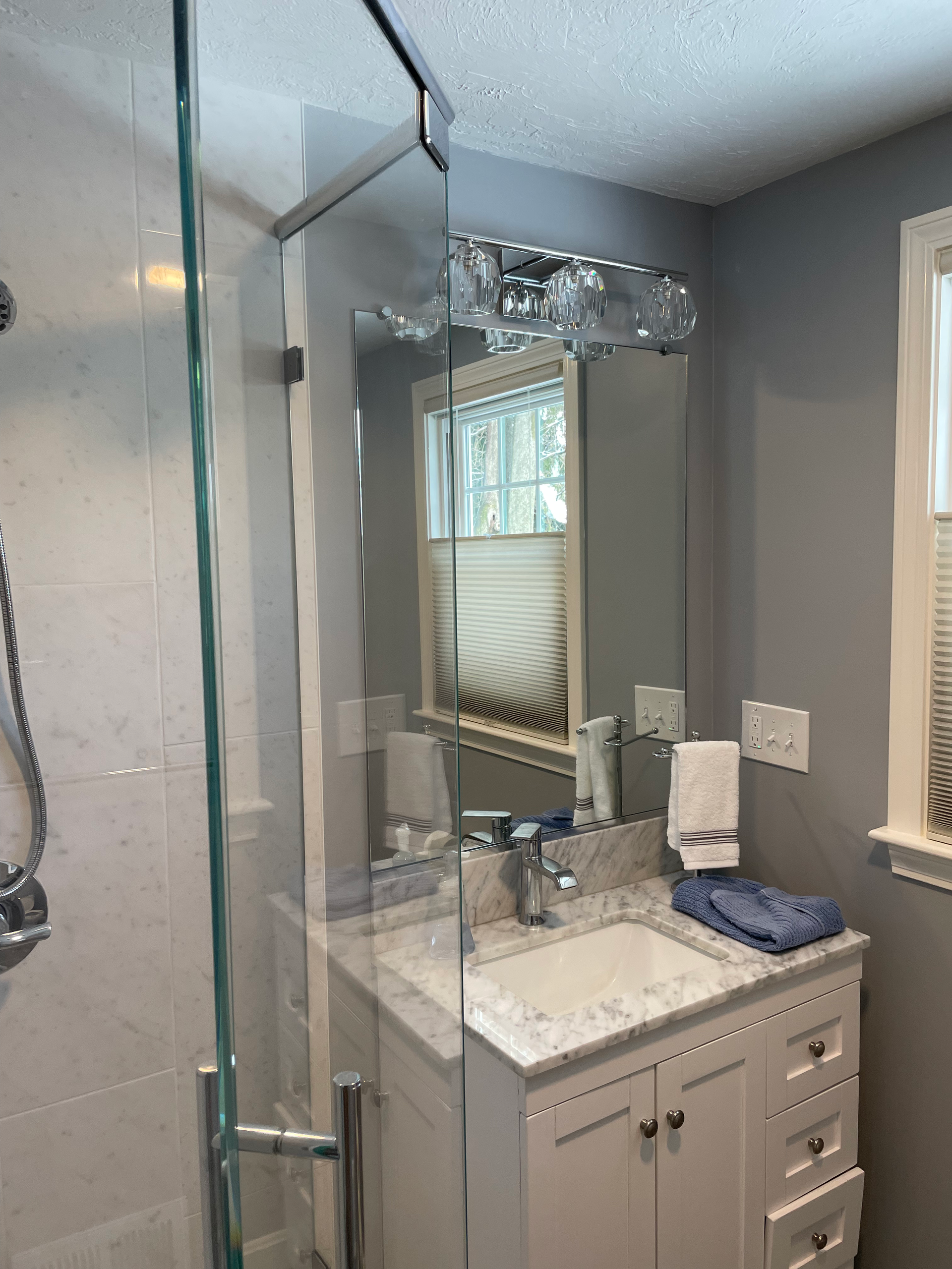 A bathroom with a sink , mirror and shower.