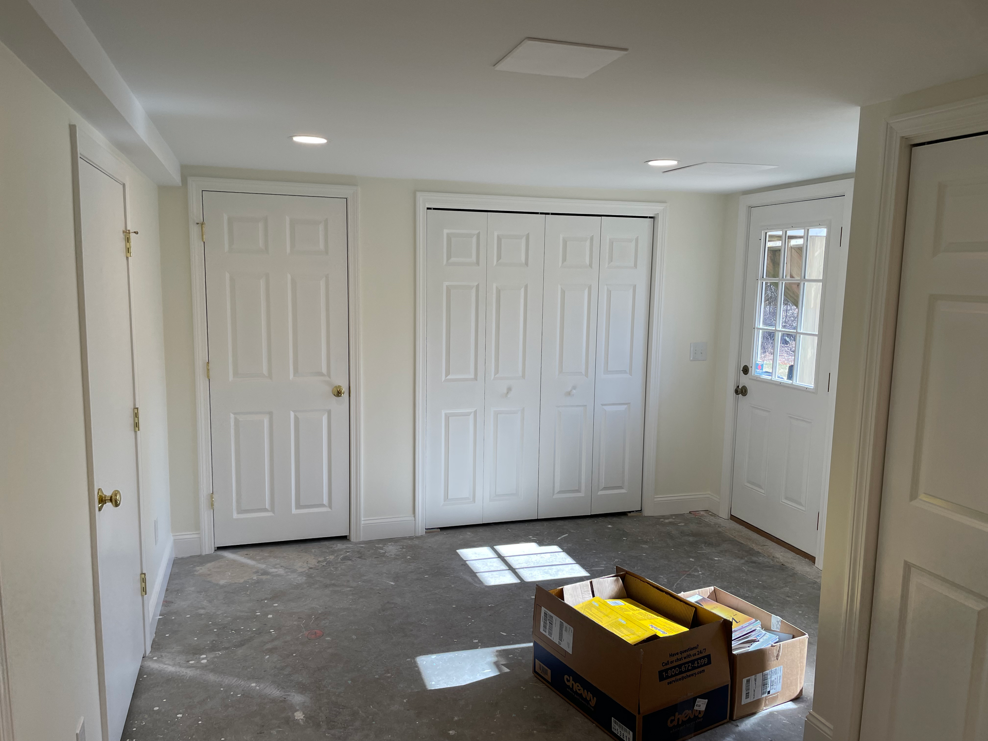 An empty room with white doors and a box on the floor.