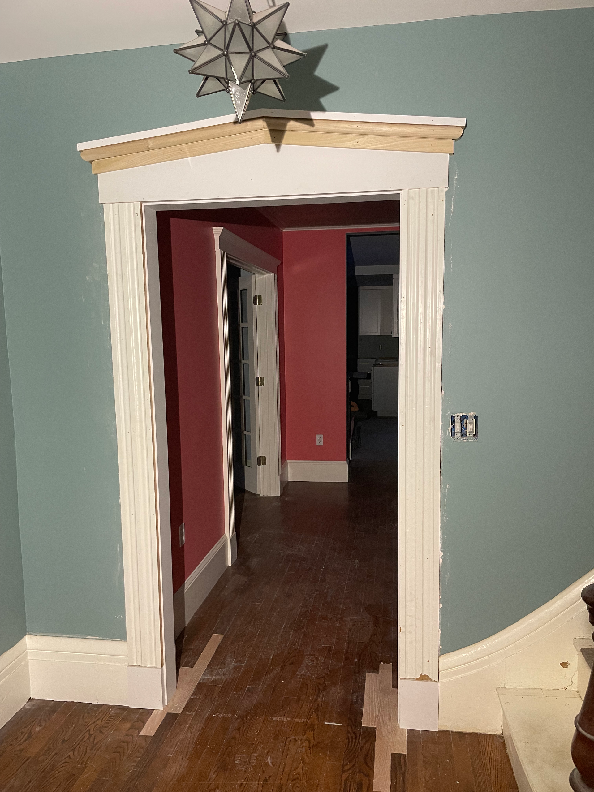 A hallway with pink walls and a white door with a star on top of it.