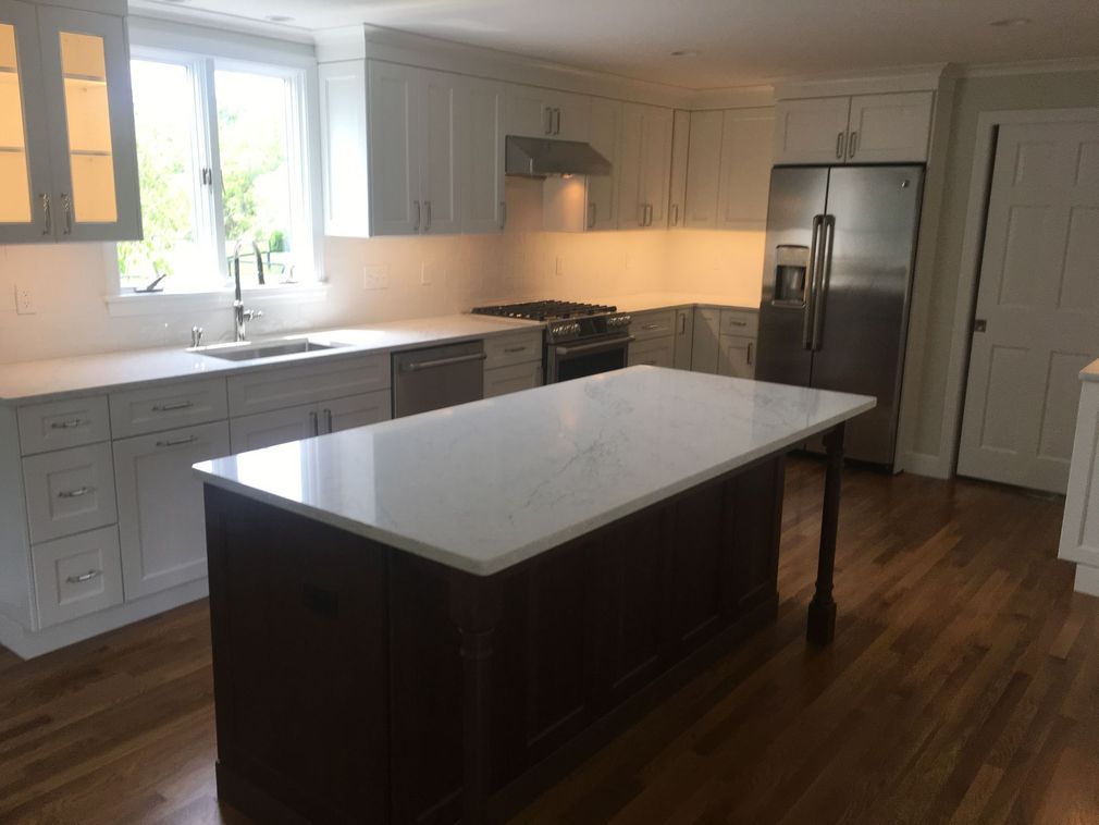 Modern kitchen with white cabinets, stainless steel appliances, and a dark island with a white countertop.