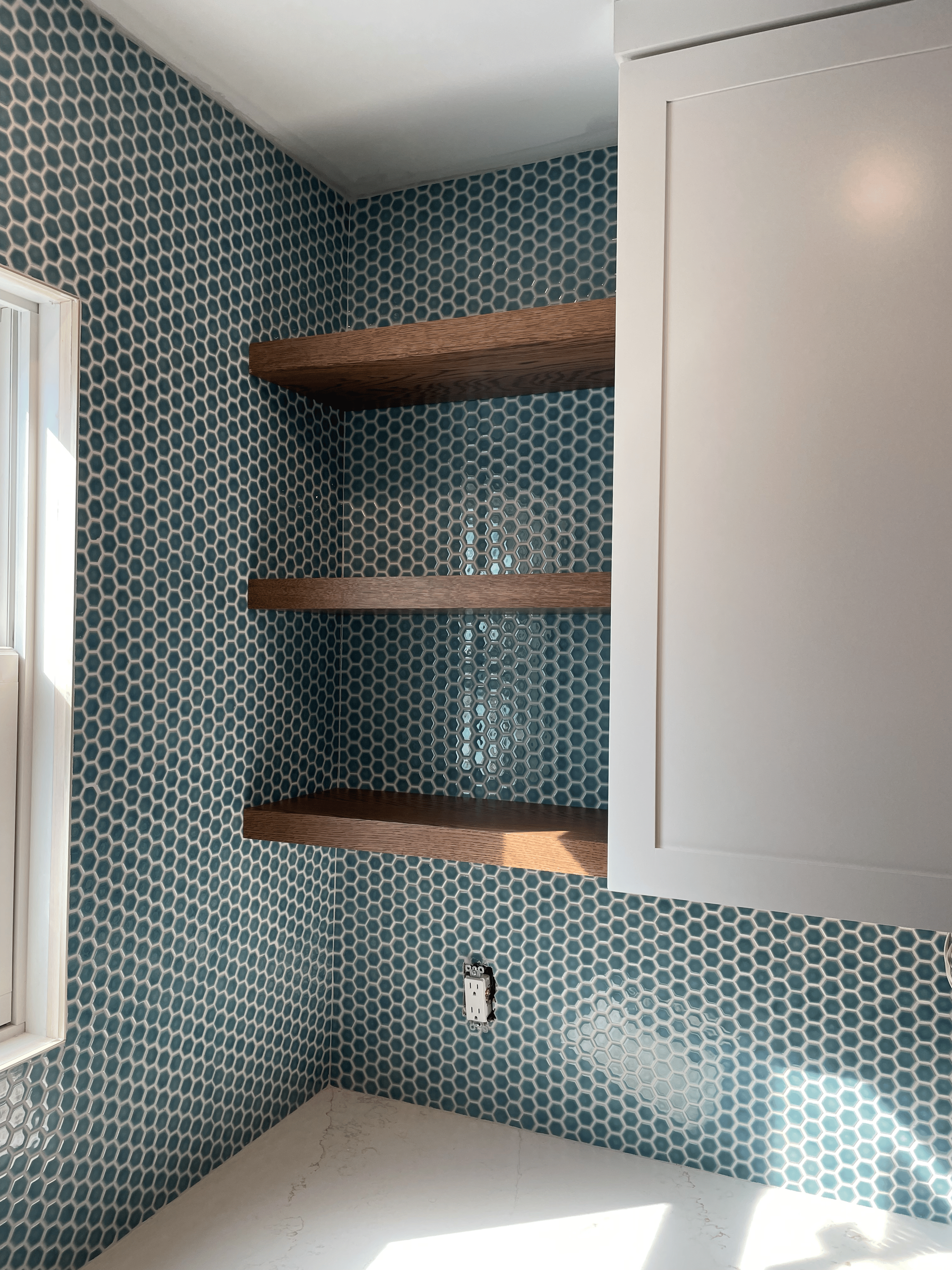 A bathroom with blue tiles and wooden shelves