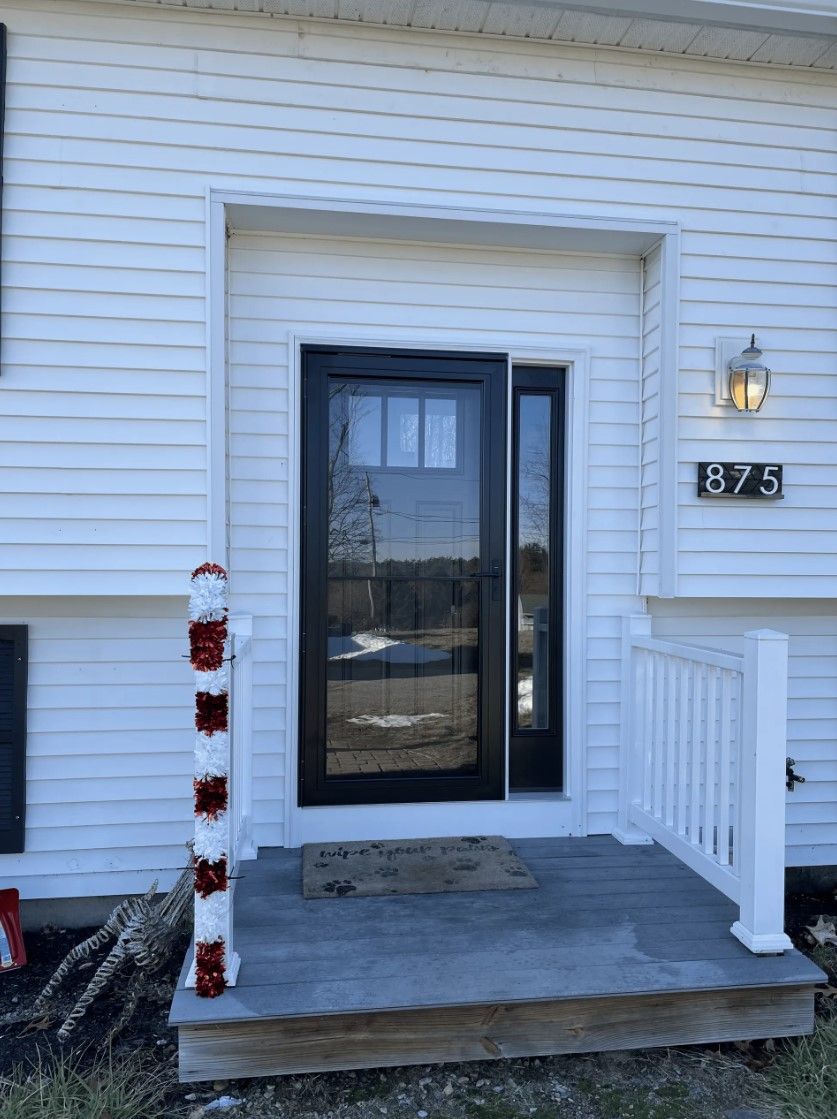 Black door on a gray porch, white siding and trim. Address 875 visible.
