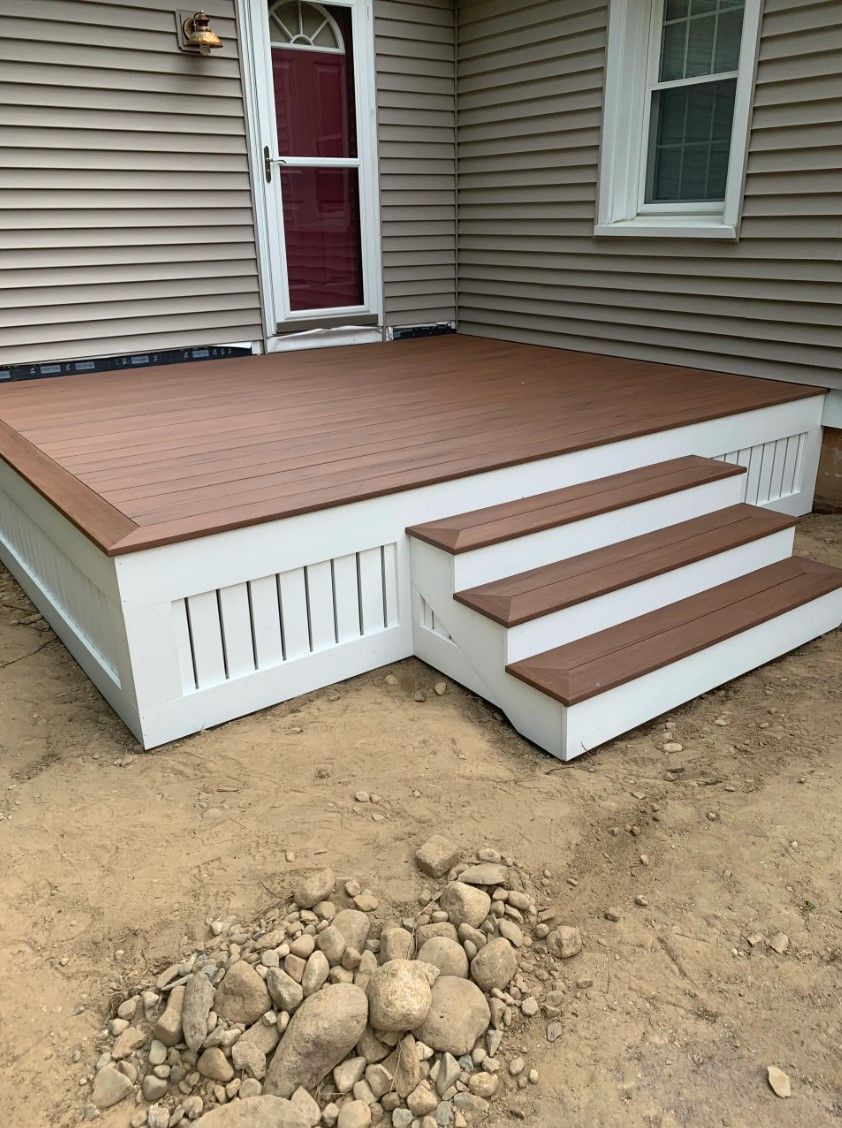 Newly built deck with three steps, brown decking, white trim, and a red door.