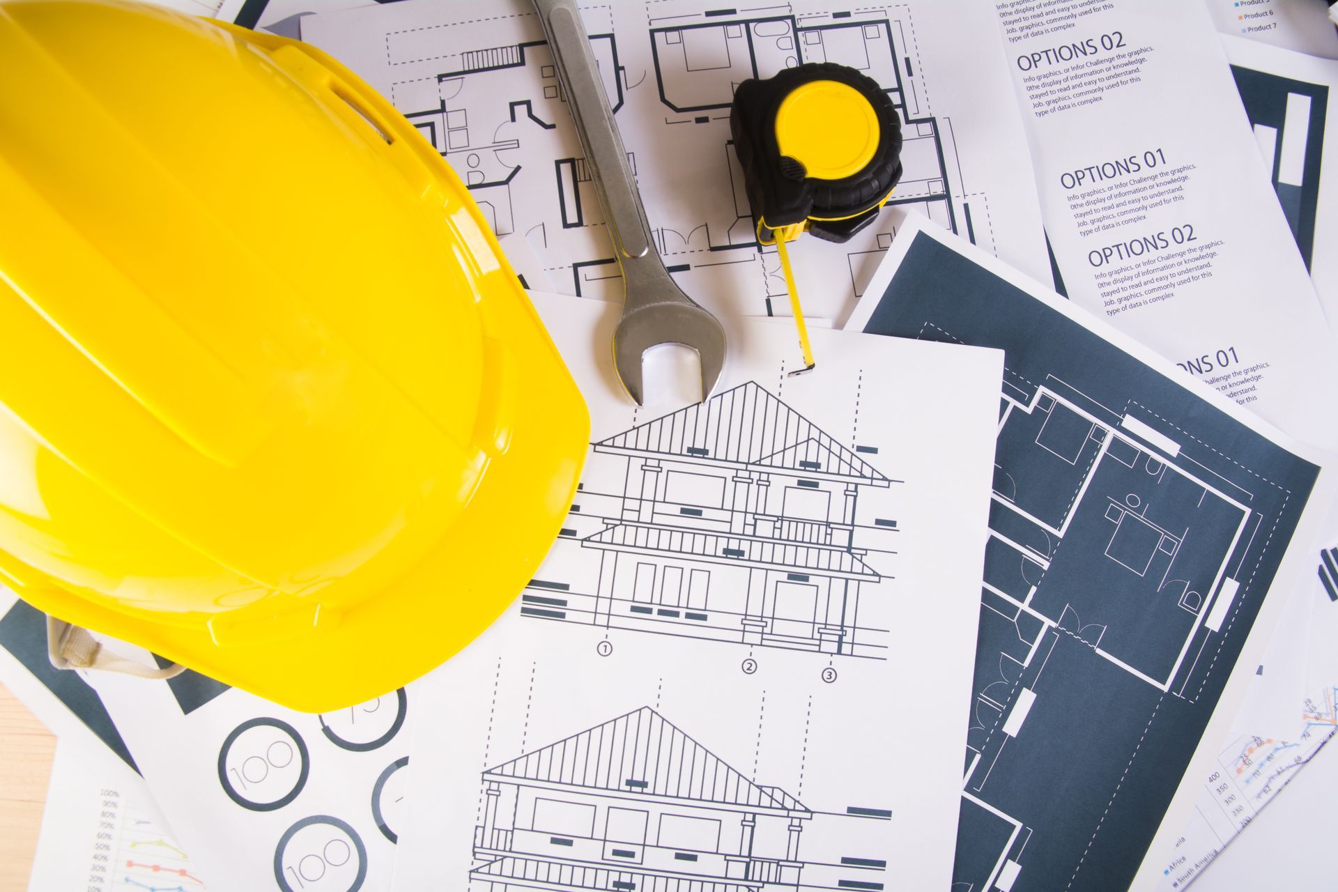 A yellow hard hat is sitting on top of a table next to a tape measure and wrench.