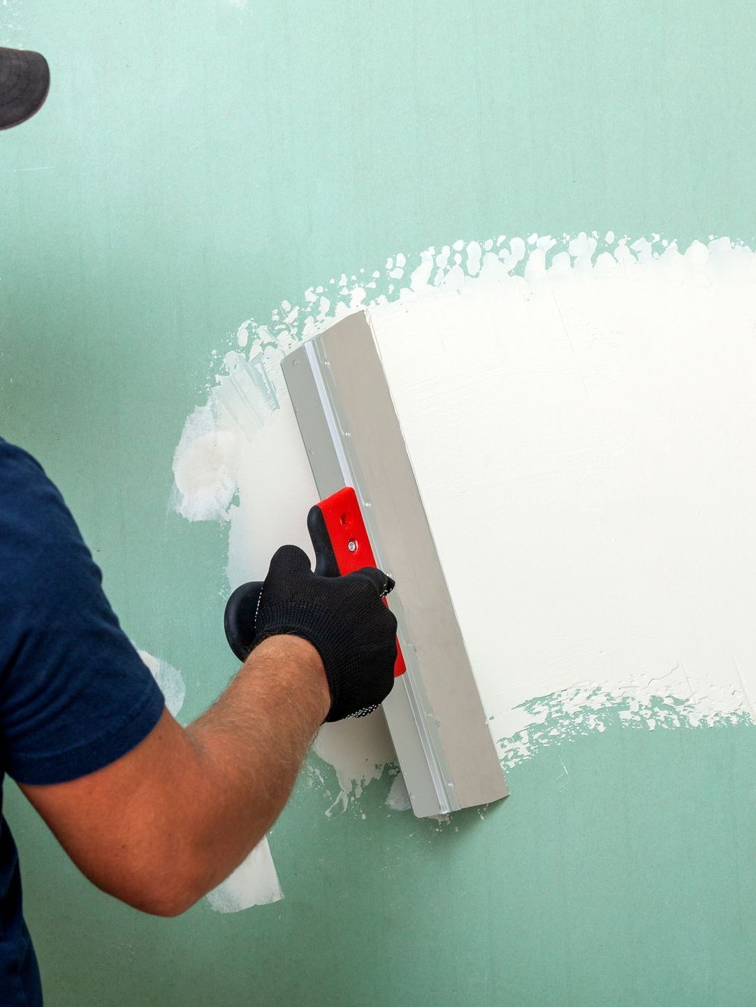 A man is plastering a wall with a spatula.