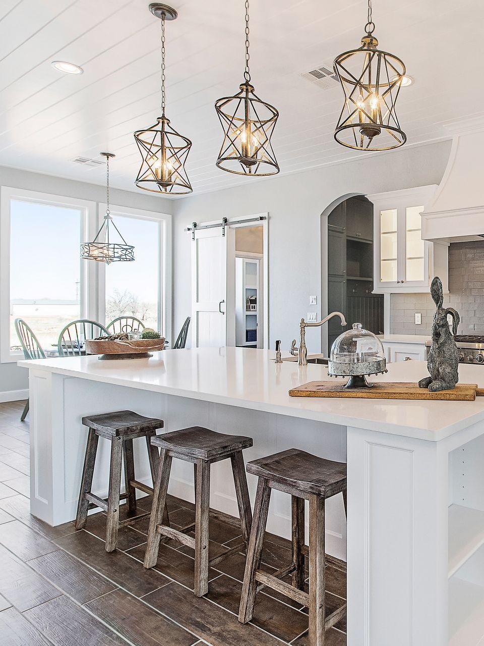 A kitchen with a large island and wooden stools.