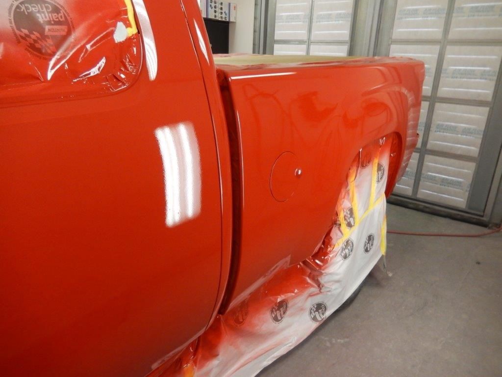 Red truck bed being painted in a body shop.