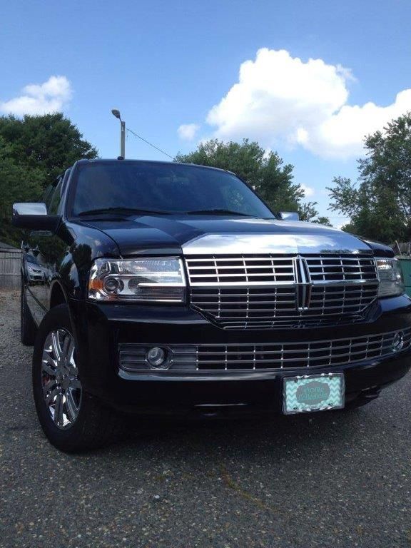 Black Lincoln Navigator SUV with chrome accents parked outdoors on a sunny day.