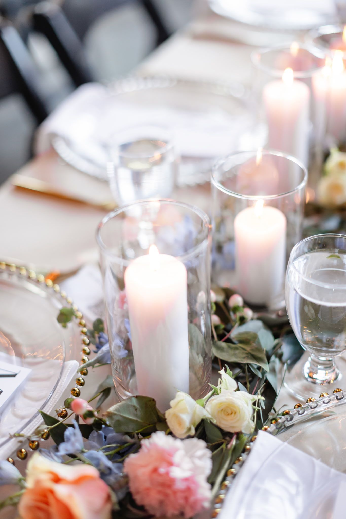 A table set for a wedding reception with candles and flowers on it.
